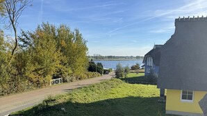 A residential area with a house, a pathway, and a lake in the background. - Vacation apartment Kajüte 2 - close to the harbor, with balcony - Fully equipped (Poseritz)