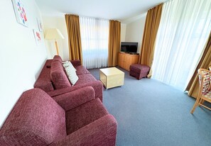 A living room with a sofa set, a coffee table, a TV stand, and a wooden cabinet. - Apartment 22 in Haus Hühnergott - Balcony with a view - Apartment 22 Sellin - (Sellin)