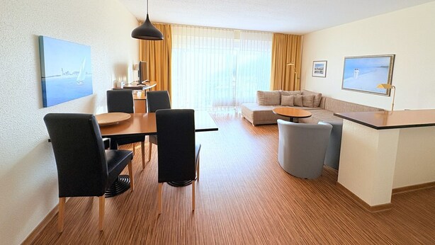 A modern hotel room with a dining area, a sofa, and a small kitchen area. - Boddenhof Apartment 48 - Terrace for dog lovers - Holiday apartment 48 - (Bergen)