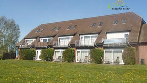 A row of townhouses with a grassy lawn in front. - Boddenhof Apartment 48 - Terrace for dog lovers - Holiday apartment 48 - (Bergen)
