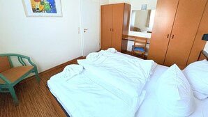 A bedroom with a bed, a chair, a wardrobe, and a desk. - Boddenhof Apartment 48 - Terrace for dog lovers - Holiday apartment 48 - (Bergen)