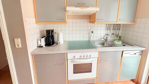 Ett kompakt kök med en inbyggd ugn, en kaffebryggare, en brödrost och ett handfat.