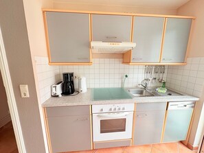 Ett kompakt kök med en inbyggd ugn, en kaffebryggare, en brödrost och ett handfat.