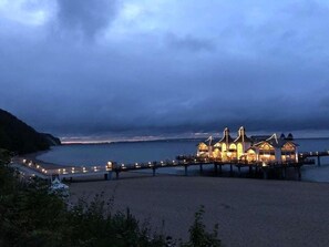 A coastal hotel with a pier extending into the sea, featuring multiple buildings with illuminated facades. - Apartment Meeresrauschen - with 2 balconies and forest view - Meeresrauschen - Comfort (Baabe)