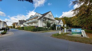 Ein modernes Wohngebäude mit zweistöckiger Bauweise, einem überdachten Balkon und blauem Himmel.