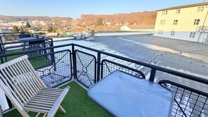 En takterrass med ett bord och stolar, utsikt över en stadsbild och en byggnad i bakgrunden.