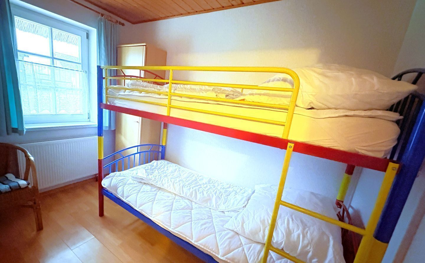 A bunk bed room with a window, radiator, and a chair.