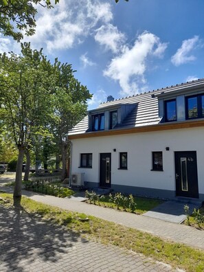 A modern two-story building with a flat roof, large windows, and a paved driveway. - Vacation home BUG - between Bodden and sea - Holiday home Bug - Charming domicile (Dranske)