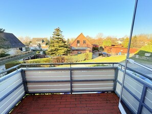 A balcony with a view of a residential area, including houses and a tree. - Vacation home Carlo - renovated 2025, top location, for animal lovers - dog friendly (Glowe)