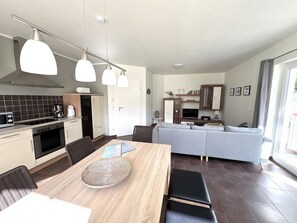 A modern kitchen with a dining area, a sofa, and a television in the living room. - House Sanddorn - Vacation dream for humans and animals - Ferienhaus Sanddorn - Ihr (Breege-Juliusruh)