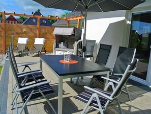 En udendørs terrasse med et bord, stole og en parasol.