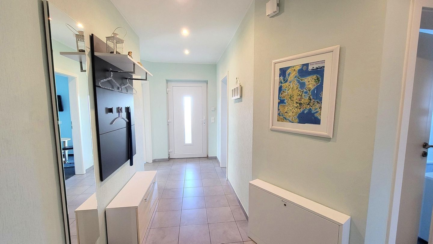 A hallway with a kitchen area, a door at the end, and a framed map on the wall.