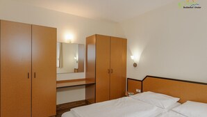 Hotellihuone, jossa on sänky, vaatekaappi, peili ja yöpöytä.