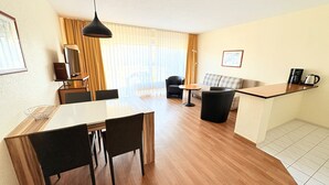 Moderni hotellihuone, jossa on ruokailutila, sohva ja keittiötaso.
