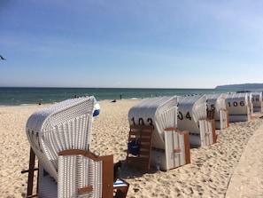 Strandstolar med nummer på, placerade på sanden nära vattnet.