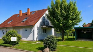 A white building with a red-tiled roof, a balcony, and a sign reading 'Ruigen.' - Vacation home zum Kranichblick - for families + dog - Zum Kranichblick: Relaxing (Garz OT Losentitz)