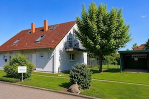 Un bâtiment blanc avec un toit recouvert de tuiles rouges, un balcon et une enseigne sur laquelle on peut lire « Ruigen ».