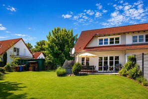 Il s’agit d’une propriété résidentielle dotée d’une pelouse bien entretenue, d’une terrasse avec mobilier d’extérieur et d’un grand arbre en arrière-plan.