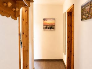 Un couloir avec des portes en bois, un tableau encadré au mur et un plafond en bois.