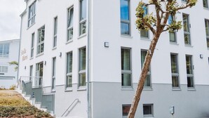 Ein modernes Gebäude mit einer flachen Fassade, zahlreichen Fenstern und einer Treppe, die zum Eingang führt.