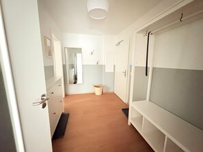 A narrow hallway with a wooden floor, white walls, and a mirror on the left. - Stella Maris apartment 3 - close to the beach, for families - Stella Maris 3 - Living with (Binz)