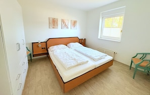 Camera da letto con un letto, un comodino, una sedia, una finestra e decorazioni a parete.