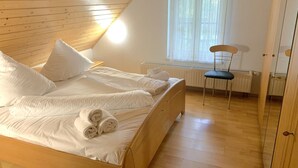 Een slaapkamer met twee bedden, een raam met gordijnen, een radiator en een stoel.