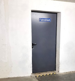 Puerta cerrada con un letrero que dice "Fahrraum" en una pared blanca.