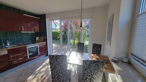 Eine moderne Küche mit Essbereich, großen Fenstern und Blick ins Freie.