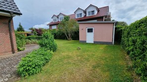 A residential area with a brick house, a small pink building, and a well-maintained lawn. - Windland Vacation Home—with a garden, fireplace, and sauna—A cozy vacation home (Dranske)