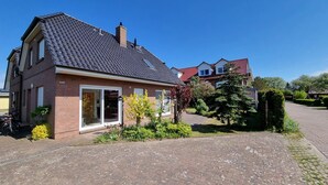 Een huis met twee verdiepingen, met een bakstenen gevel, een pannendak en een oprit naar de ingang.