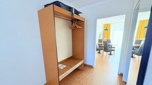 A room with a bunk bed, a small table, and a chair. There is a dining area with tables and chairs visible through an open door. - Boddenhof Apartment 46 - ground floor, pet-friendly - Holiday apartment 46 - Helles (Bergen)