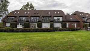 A two-story residential building with a flat roof, multiple balconies, and a well-maintained lawn. - Boddenhof Apartment 46 - ground floor, pet-friendly - Holiday apartment 46 - Helles (Bergen)