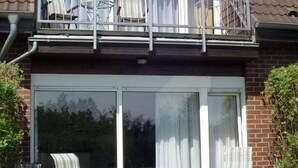A residential balcony with a glass door, two chairs, and a small table. - Boddenhof Apartment 46 - ground floor, pet-friendly - Holiday apartment 46 - Helles (Bergen)