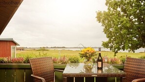 A table with chairs on a balcony overlooking a field. - Apartment 3 in the Zeesboothaus- balcony, view, sauna - Apartment 3 in the Zeesboothaus (Middelhagen)