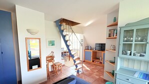 Uma sala de estar ampla com escada, televisão e um armário com copos.