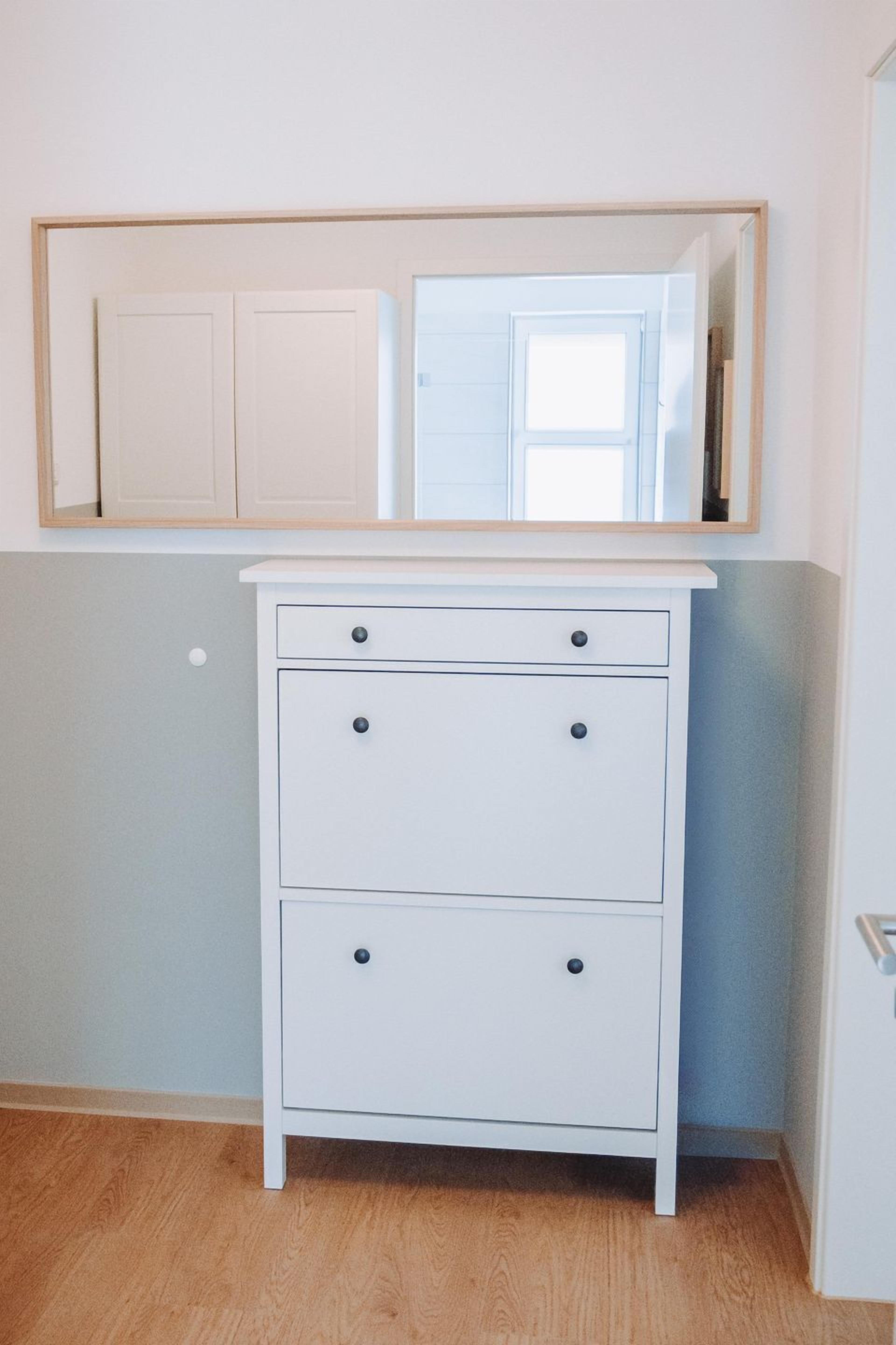 A white dresser with three drawers and a mirror above it.