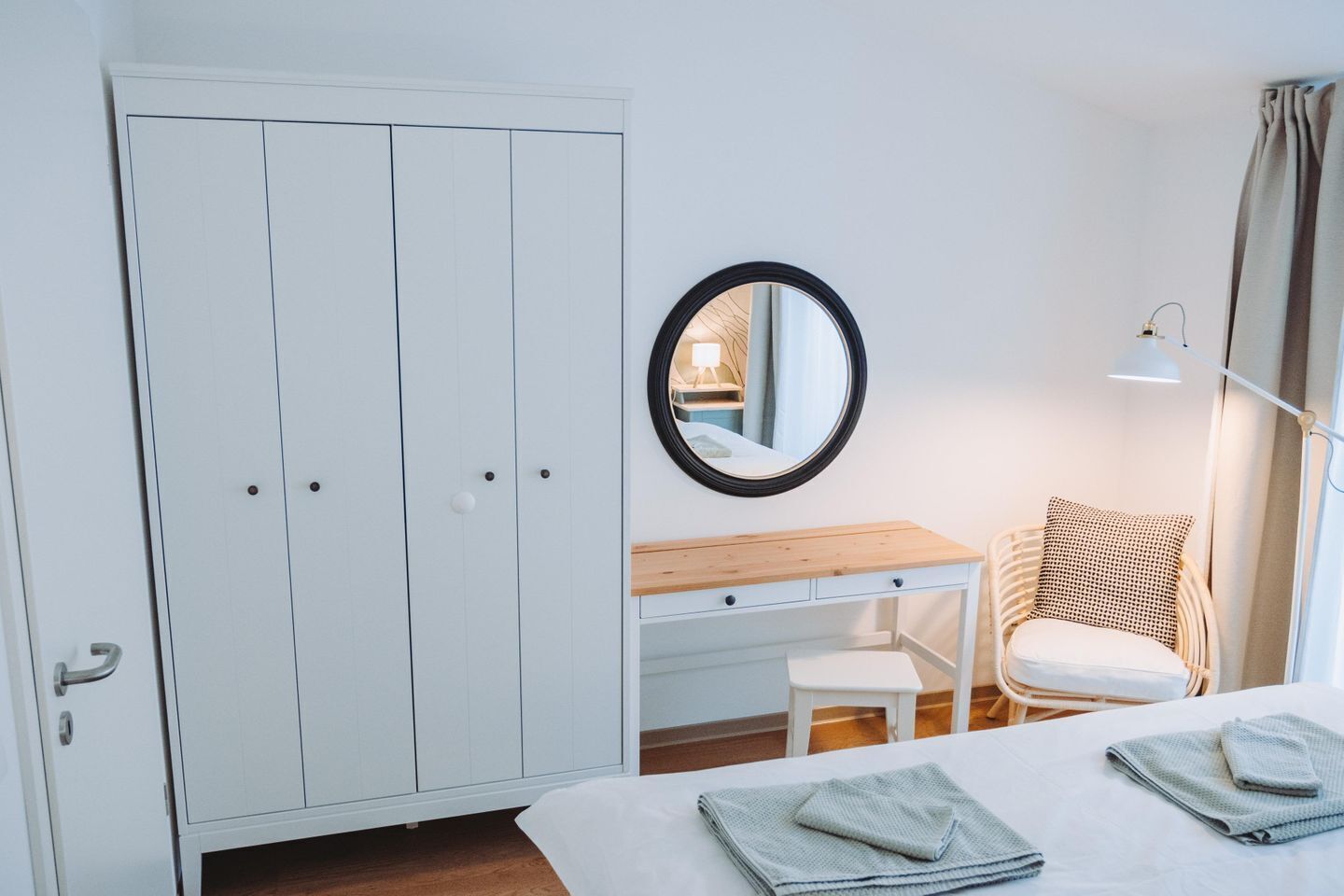Une chambre avec une armoire, une table de chevet, une chaise et un lit avec des serviettes.