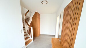 Un pasillo con una escalera de madera, un banco de madera y un revestimiento de paneles de madera.