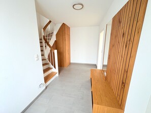 Ein Flur mit einer Holztreppe, einer hölzernen Bank und einer Wand aus Holzpaneelen.