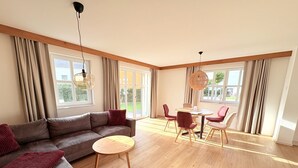 Una sala de estar moderna con un sofá modular, una mesa de centro redonda y un comedor con mesa y sillas.