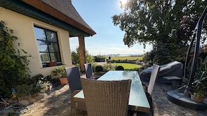 Une terrasse extérieure aménagée avec des meubles en osier, une table et un espace barbecue.