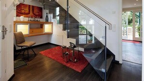 Un intérieur moderne avec un escalier, un bureau en bois, une chaise et un tapis rouge.