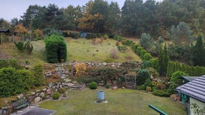 Un jardín con un muro de piedra, una banca y un cobertizo pequeño.