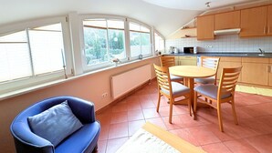 Una cocina compacta con comedor, ventanas amplias y una silla azul.