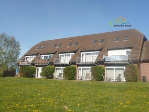 A row of townhouses with a grassy lawn in front. - Boddenhof Apartment 52 - Balcony, dog-friendly - Apartment 52 - (Bergen)