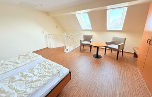 A bedroom with a bed, a small round table, two chairs, and a skylight. - Boddenhof Apartment 52 - Balcony, dog-friendly - Apartment 52 - (Bergen)