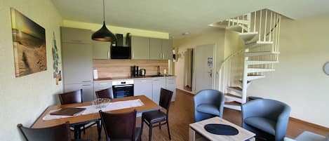 A compact living space with a dining area, kitchen, and a spiral staircase.
