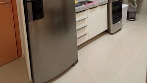 Cozinha moderna com eletrodomésticos de aço inoxidável, micro-ondas e painel de azulejos.