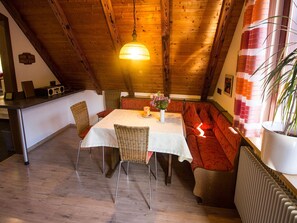 A cozy dining area with a high ceiling, wooden beams, a table with chairs, and a sofa. - Holiday Apartment 'Am Hauskopf' with Shared Garden and Wi-Fi (Oppenau-Lierbach)